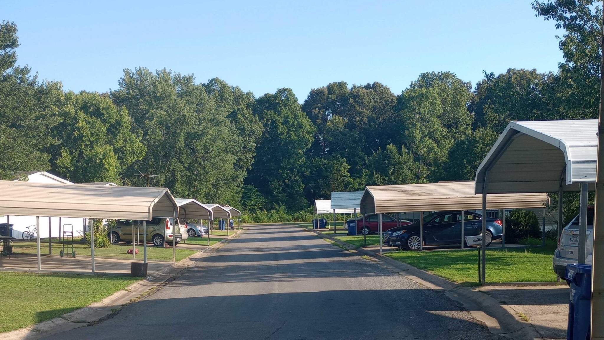 A road in Glenbriar Mobile Home Park during autumn, lined with mobile homes, green lawns, and colorful trees.