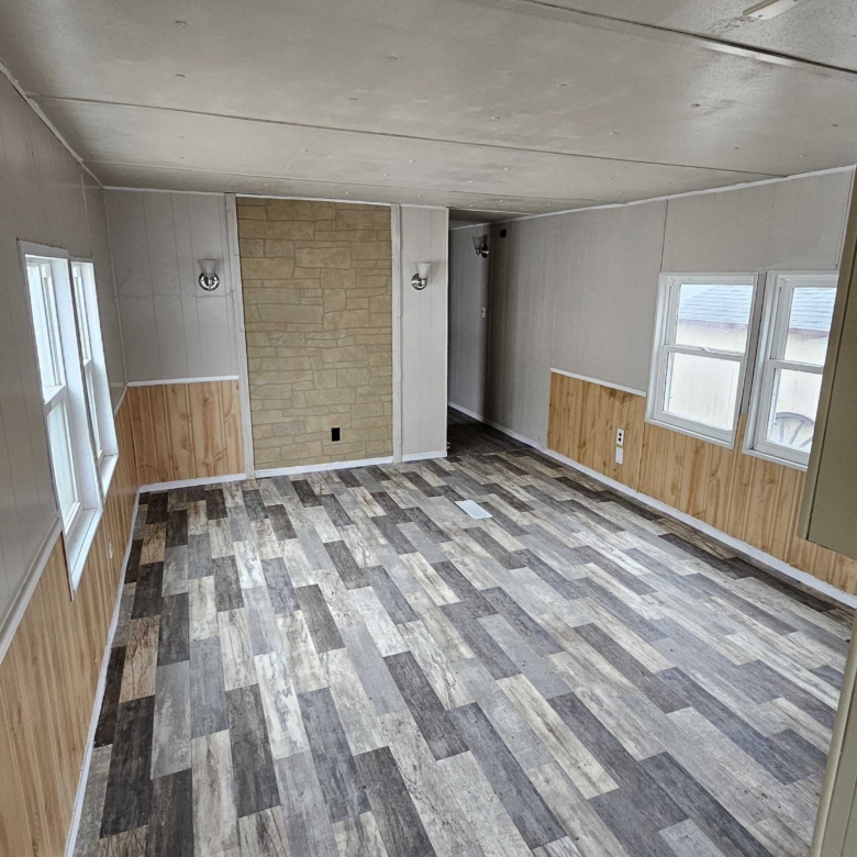 Empty living room space in a mobile home featuring large windows, ready for personalization and cozy living.