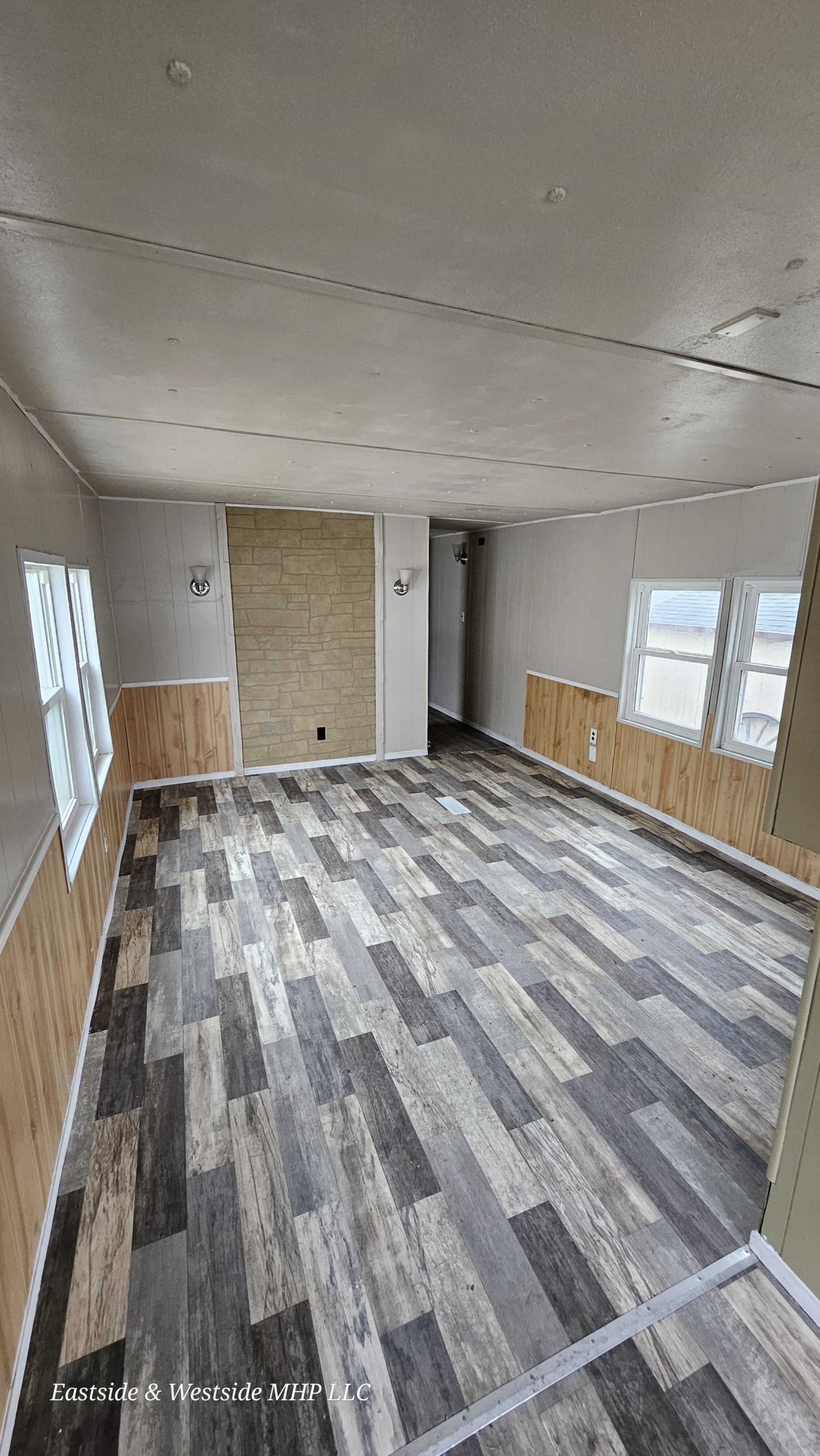 Empty living room space in a mobile home featuring large windows, ready for personalization and cozy living.