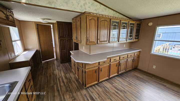 View of a well-lit kitchen with extensive wooden cabinetry and ample counter space in a mobile home, highlighting the practical and inviting layout.